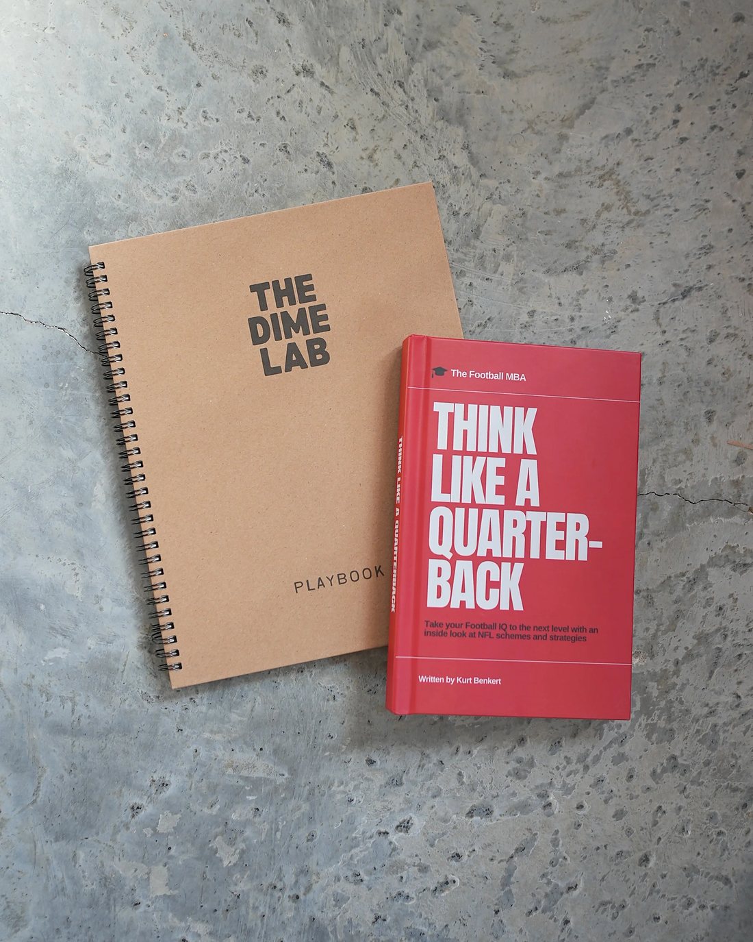The Dime Lab Playbook and the Think Like A Quarterback hardcover side by side on concrete.