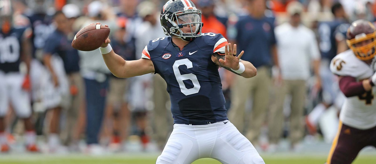 Kurt Benkert in the navy Virginia home jersey, number 6, setting to throw at Scott Stadium.